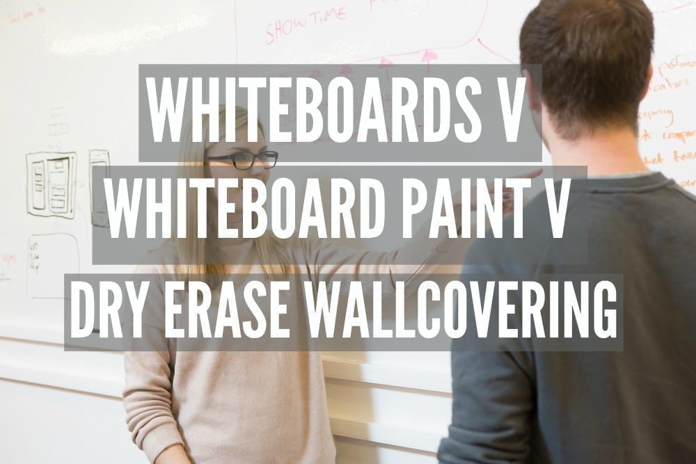 A woman and a man are problem solving while working together on dry erase whiteboard wall.